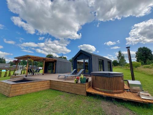 a tiny house with a hot tub and a gazebo at Rātes Krasti - Rasa - holiday house with sauna and lakeview in Lejasciems