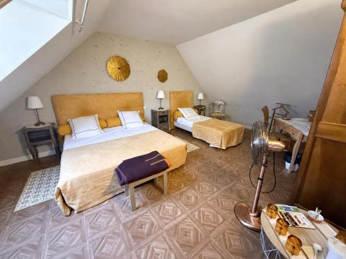 a bedroom with two beds and a table with a lamp at Chambres d'Hôtes L'Orée des Vignes in Saint-Père