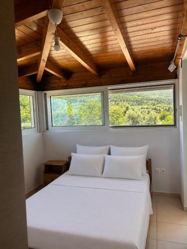 a bedroom with a large white bed with two windows at Costa Kalamos Suites in Kalamos