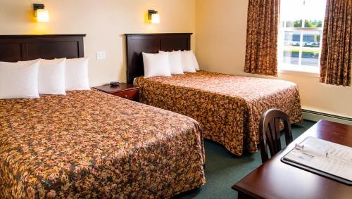 a hotel room with two beds and a table at Traveller's Inn Prince Edward Island in Summerside