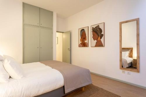 a white bedroom with a bed and a mirror at Casa em bairro típico de Aveiro in Aveiro