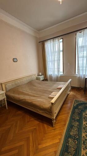 a large bed in a bedroom with wooden floors and windows at Tilda&Matilda in Kutaisi