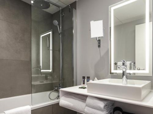 a white bathroom with a sink and a shower at Novotel Annecy Centre in Annecy