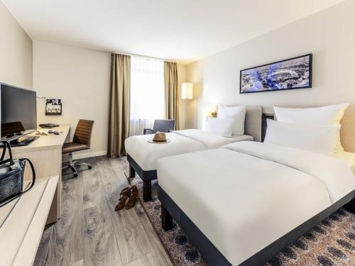 a hotel room with two beds and a television at Mercure Hotel München Süd Messe in Munich