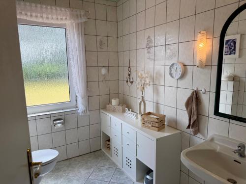 a bathroom with a sink and a toilet and a window at Fehntjer Ferienhof nahe Idasee in Ostrhauderfehn