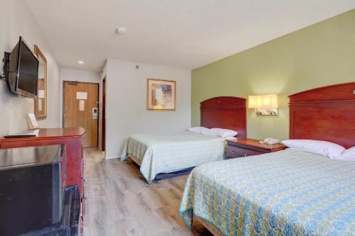 a hotel room with two beds and a flat screen tv at Coldwater Inn & Suites near I 69 in Coldwater
