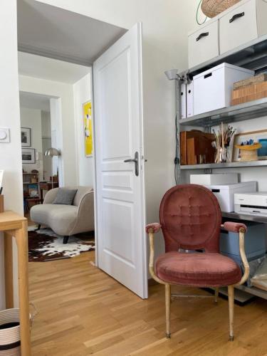 a living room with a red chair in front of a door at Bright apartment - old renovated building in Nantes