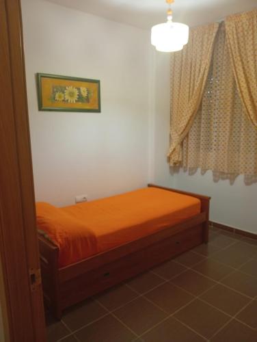 an orange bed in a room with a window at Lagunas Ruidera 9 in Ruidera