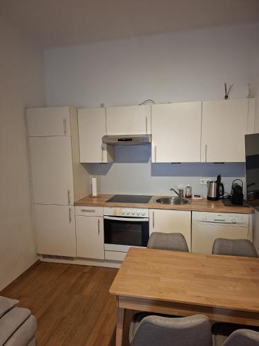 a kitchen with white cabinets and a wooden table at Apartment im Stadtzentrum in Steyr