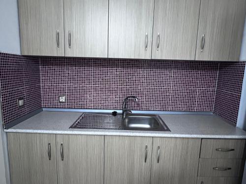 a kitchen with a sink and a red tiled wall at 360° View Apartments in Vlorë