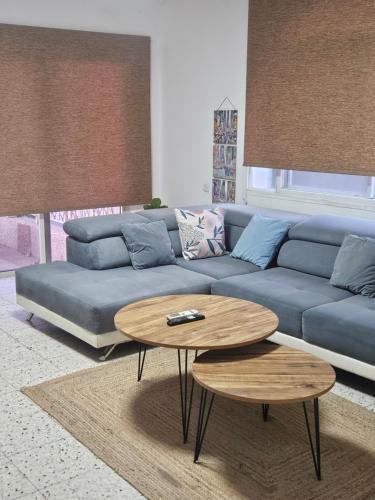 a living room with a blue couch and a table at Hofesh Yehonatan Hadas Garden Apt in Tiberias