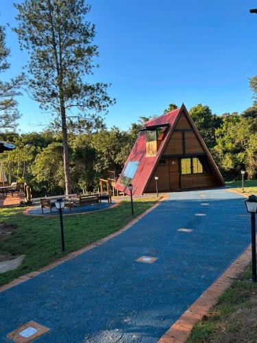 a small house with a red roof in a park at Pousada Vossa Excelência in Cajuru