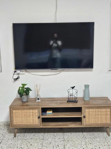 a flat screen tv sitting on top of a wooden entertainment center at Hofesh Yehonatan Hadas Garden Apt in Tiberias