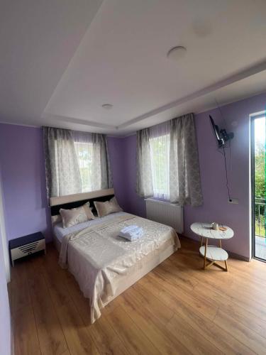 a bedroom with purple walls and a bed and a table at Paceri in Itʼkhvisi