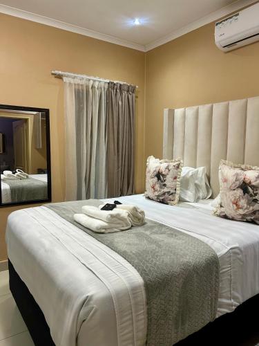 a bedroom with a large bed with towels on it at Piink Lopez in Manzini