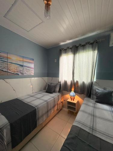 a bedroom with two beds and a lamp on a table at Hidromassagem cromoterapia ar condicionado lareira in Imbé