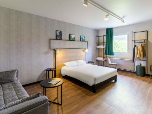 a hotel room with a bed and a couch at ibis Falaise Coeur de Normandie in Falaise