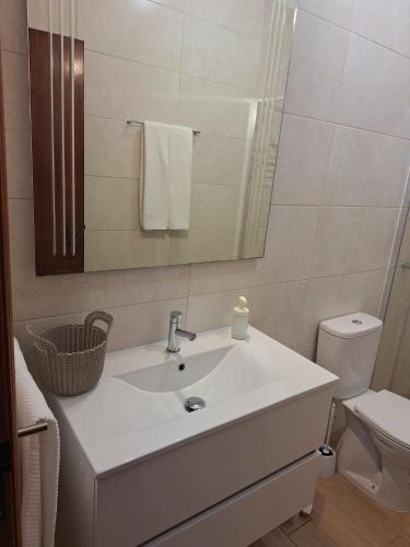 a bathroom with a sink and a mirror and a toilet at Casa Reis in Odeceixe