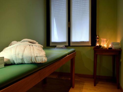 a green room with a bench and two windows at Mercure Reggio Emilia Centro Astoria in Reggio Emilia
