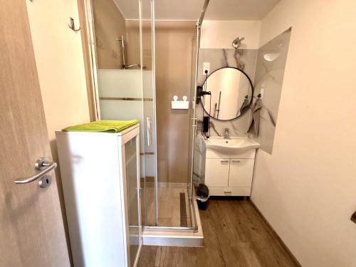 a bathroom with a shower and a sink and a mirror at Tutti Apartman in Balatonlelle