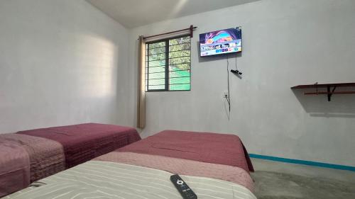 a bedroom with two beds and a tv on the wall at Casa ie in Santa María Azompa
