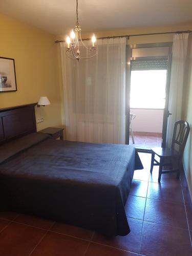 a bedroom with a bed and a chair and a window at APARTAMENTOS Hotel TurMo in Labuerda