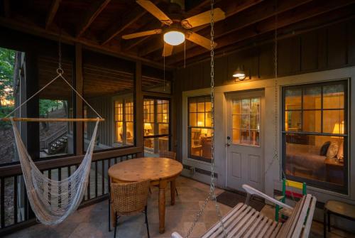 a porch with a hammock and a table and chairs at - Dawsonville, GA - Take in Beautiful Lake Views, Kick Off a Game of Foosball, Cozy Up by the Fireplace, and Unwind on the Scree in Dawsonville