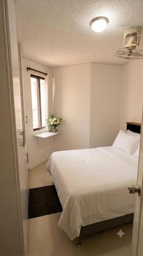 a bedroom with a white bed and a window at Tu refugio ideal cerca al mar in Playa Bello Horizonte