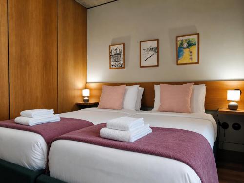 two beds in a hotel room with towels on them at Fervença Apartments in Vila Nova de Gaia