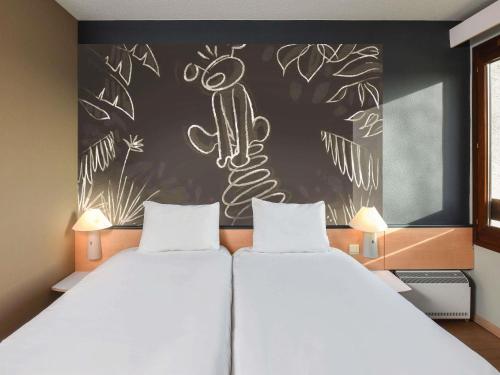 a bedroom with two beds and a wall with a cactus at ibis Charleroi Airport Brussels South in Charleroi
