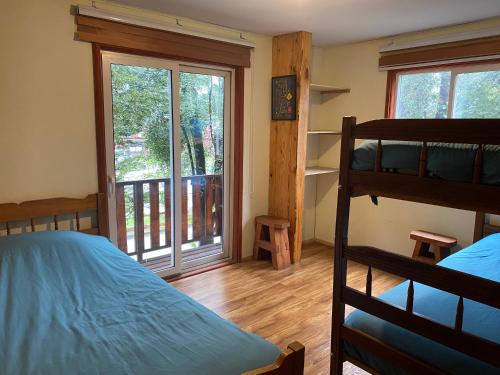 a bedroom with a bunk bed and a balcony at Hostel Raíz Del Pillán in Pucón