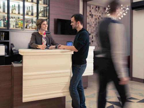 a man and woman standing at a counter in a bar at Mercure Lyon Centre Beaux-Arts in Lyon