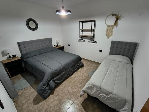 a bedroom with two beds and a mirror on the wall at Alojamiento Pasaje Montes in Cruz del Eje