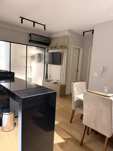 a kitchen with a counter and chairs in a room at Apê 64 Bela Vista com ar condicionado e garagem in Espirito Santo Do Pinhal