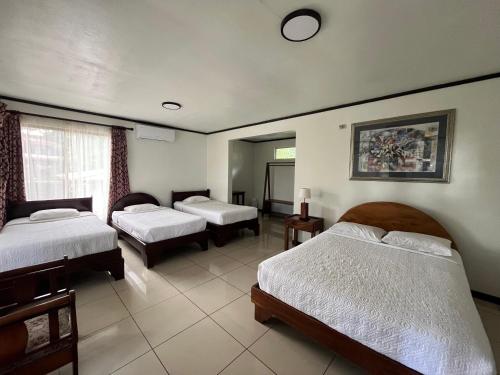 a room with three beds and a window at Brillasol Airport Hotel in Alajuela