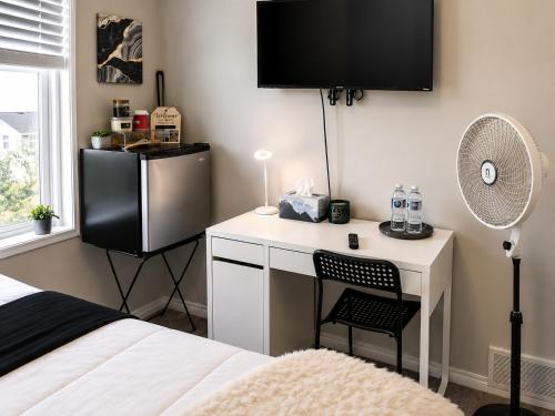 a bedroom with a desk with a fan and a bed at Southside Haven Edmonton in Edmonton