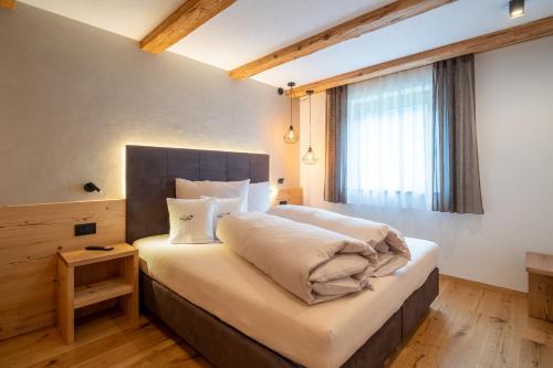 a bedroom with a large bed and a window at Lüch dl Chessl - Kesslhof in San Martino in Badia