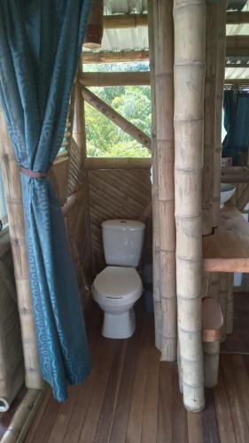 a bathroom with a toilet in a wooden house at Cabañas la pradera in Ruiosucio