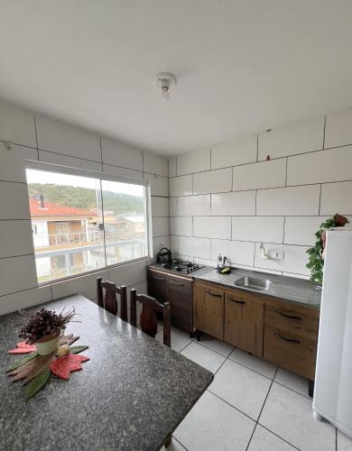 a kitchen with a table and a sink and a refrigerator at Apartamento em Garopaba in Garopaba