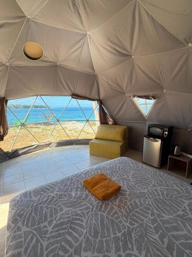 a bedroom in a tent with a bed and a chair at Dôme en face de la Passe de Tiputa in Rangiroa