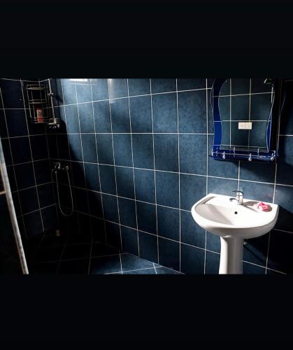 a blue tiled bathroom with a toilet and a sink at Sea Breeze House Ureki in Ozurgetʼi