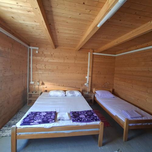a bedroom with two beds in a wooden room at Cottage Kolomza in Ulcinj