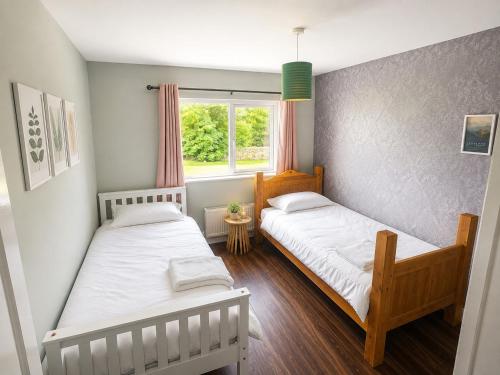 two beds in a small room with a window at Hill House Westport in Mayo