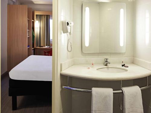 a bathroom with a sink and a bed and a mirror at ibis Goiânia in Goiânia