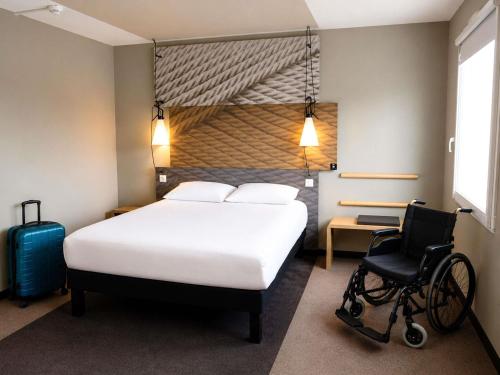 a bedroom with a bed and a wheelchair in a room at ibis Caen Porte De Bretagne in Bretteville-sur-Odon