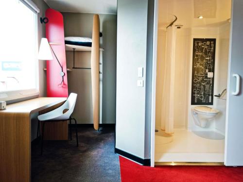 a bathroom with a toilet and a desk with a surfboard at ibis Caen Porte De Bretagne in Bretteville-sur-Odon