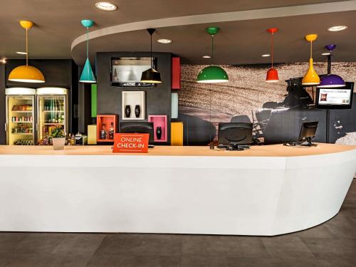 a lobby with a white counter and colorful pendant lights at ibis Sao Paulo Interlagos in São Paulo