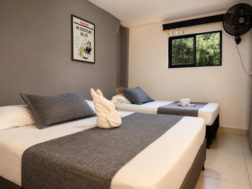 two beds sitting in a room with a window at Hotel Laureles Palo Alto in Medellín