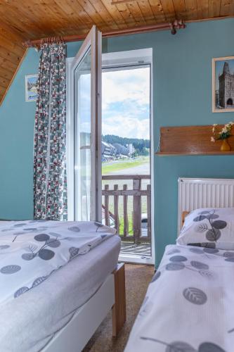 a bedroom with two beds and a balcony with a window at Horská chata LADA in Loučná pod Klínovcem