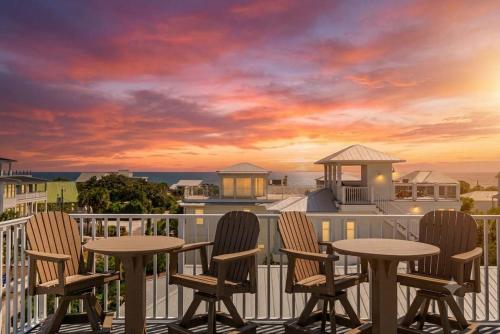 a balcony with two tables and chairs and a sunset at Blue Mountain View - Private Pool in Santa Rosa Beach